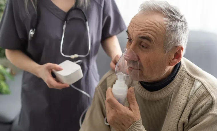 A man using a nebuliser with a nurse